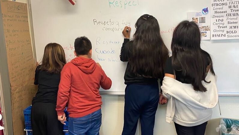 Children writing on white board